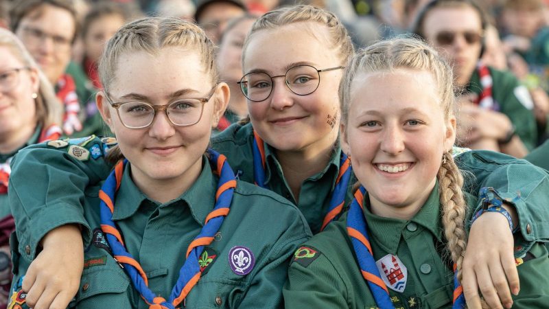 Tre spejderpiger smiler til kameraet